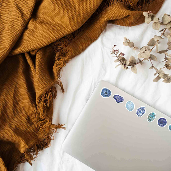 Throat Chakra Crystal Stickers on a laptop on top of a bed with a blanket