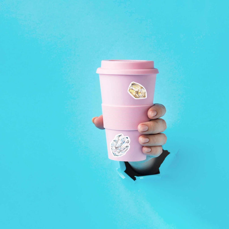 a person holding a pink to go cup with citrine stickers on it from the seven chakras watercolor sticker sheet