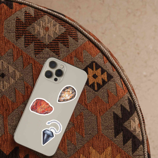 a cell phone with root chakra crystal stickers on it, sitting on a chair