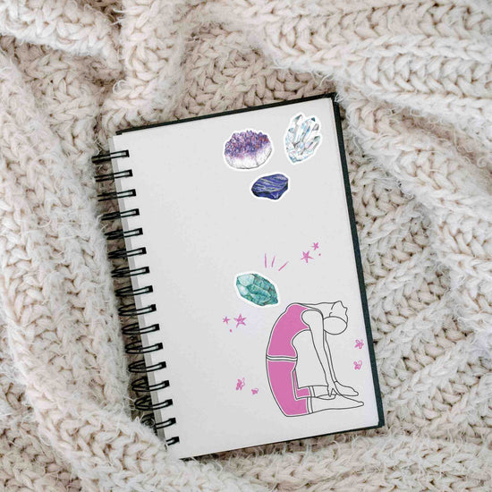 a notebook with stickers from the seven chakras watercolor sticker sheet on it, sitting on a blanket