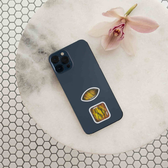 a cell phone sitting on top of a table with tigers eye stickers from the sacral chakra watercolor crystal sticker set