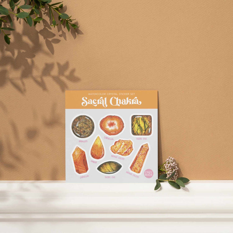a sacral chakra watercolor crystal sticker set sitting on top of a shelf next to a plant