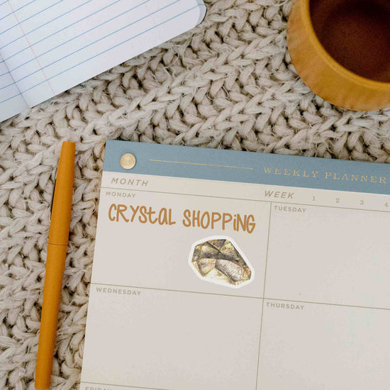 a calendar with a citrine sticker of a crystal shopping stone next to a cup