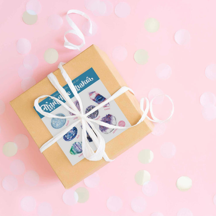 a brown box with a white ribbon on a pink background with the Third Eye Chakra Crystal Sticker Set