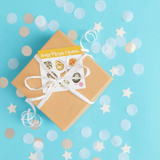 a box with a ribbon tied around it with Solar Plexus Chakra Crystal Sticker sheet on a blue background