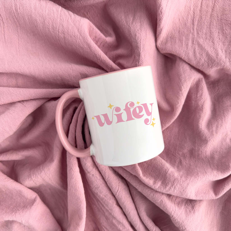 a pink coffee mug sitting on top of a pink blanket