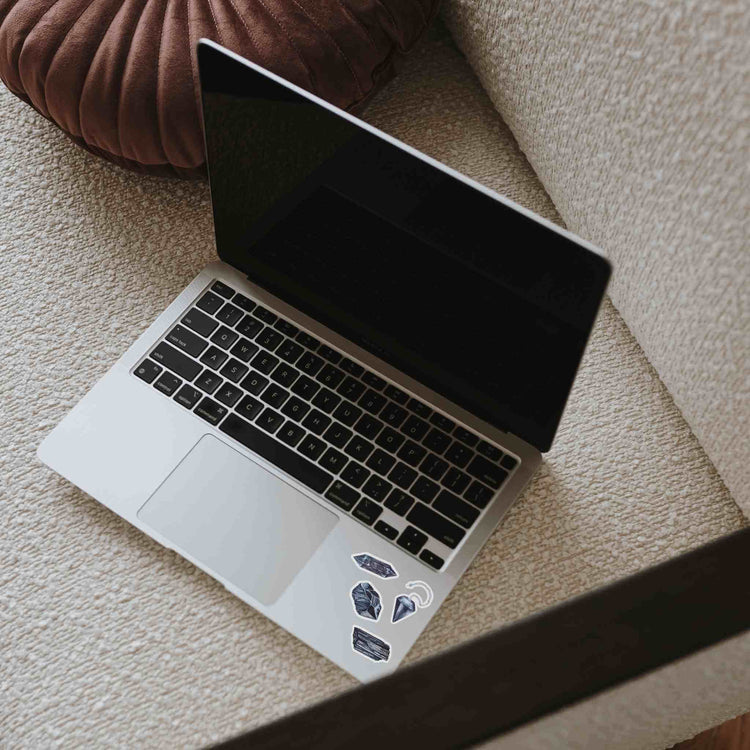 a laptop computer sitting on top of a table with Root Chakra Crystal Stickers