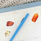 a blue pen sitting on top of a calendar with jasper, citrine, and carnelian stickers 