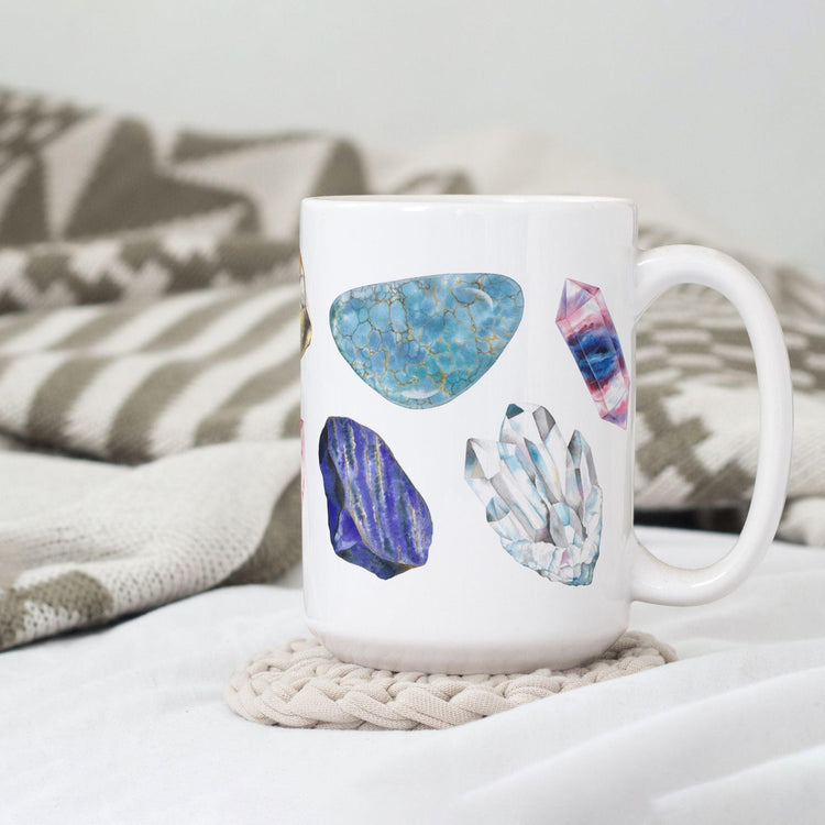 a white coffee mug with a picture watercolor crystals representing the 7 chakras