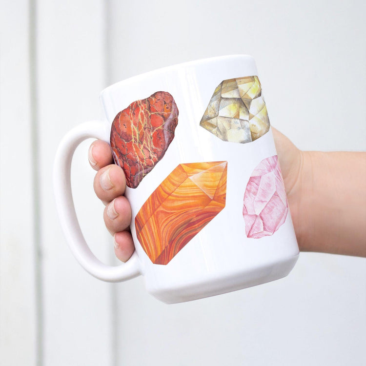 a white coffee mug with a picture watercolor crystals representing the 7 chakras