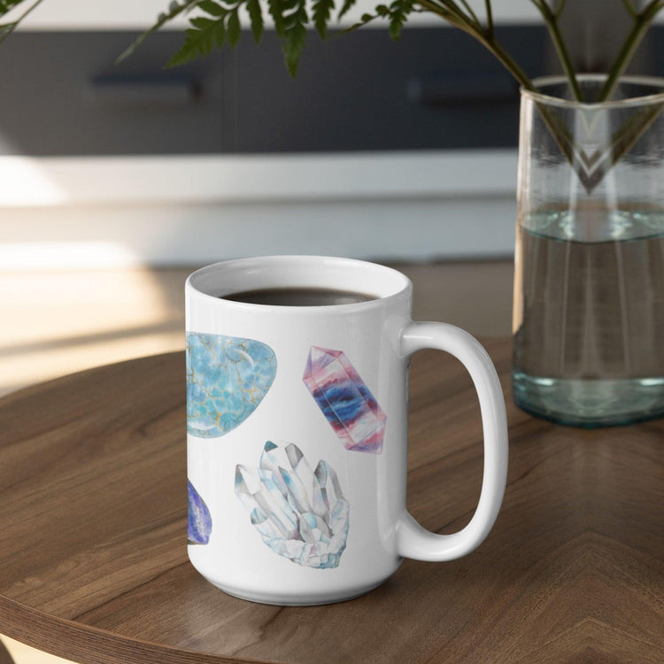 a white coffee mug with a picture watercolor crystals representing the 7 chakras